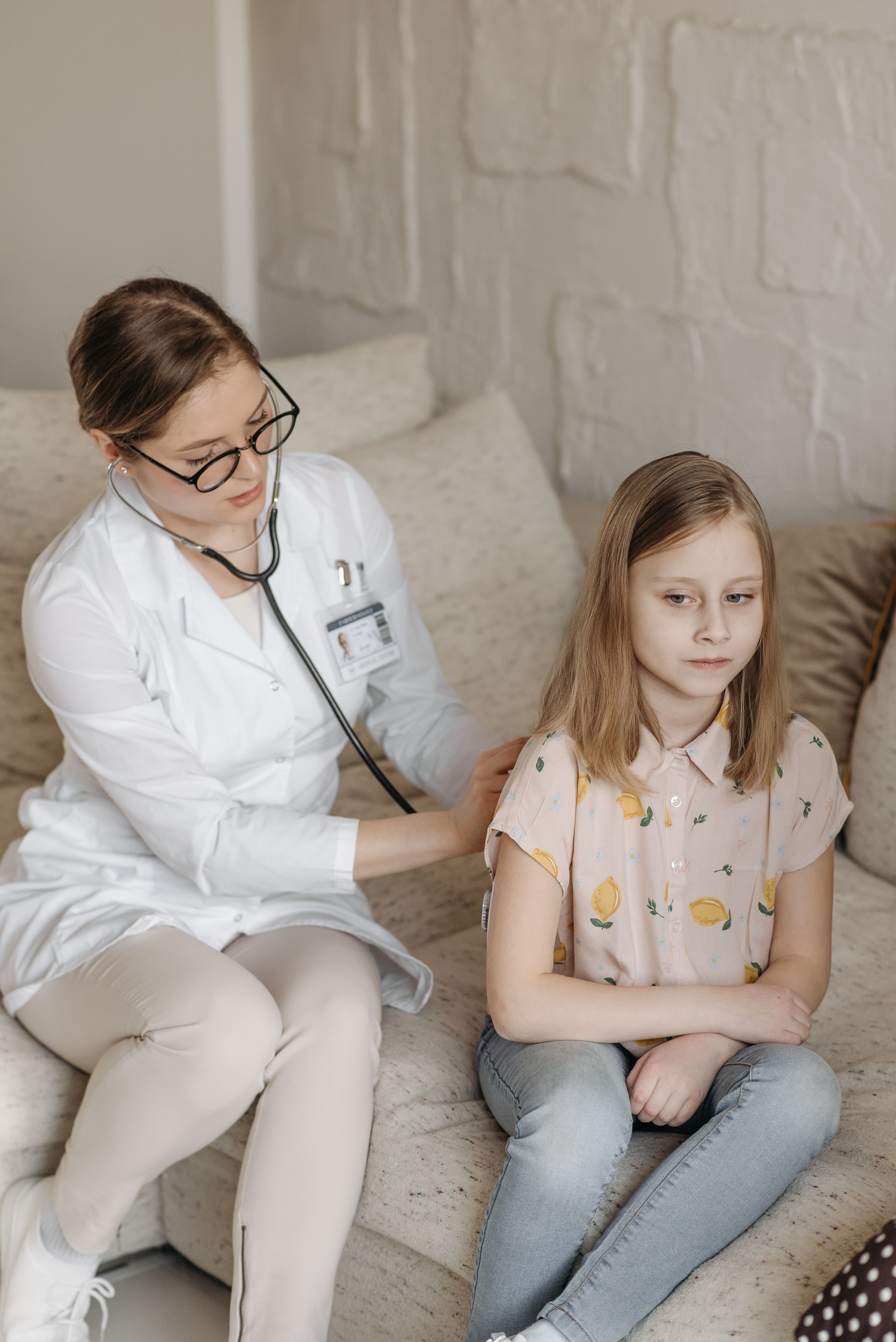 Bir doktor küçük bir hastayı evde nazikçe muayene ediyor